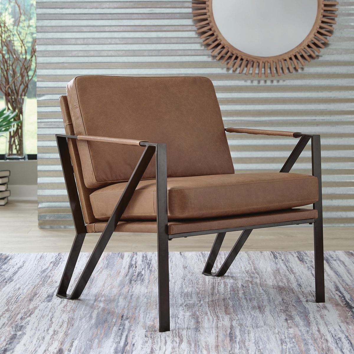 Brown armchair with metal frame against a striped wall with a round mirror.