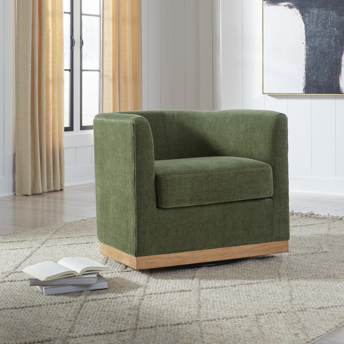 Green armchair in a room with a window and abstract painting