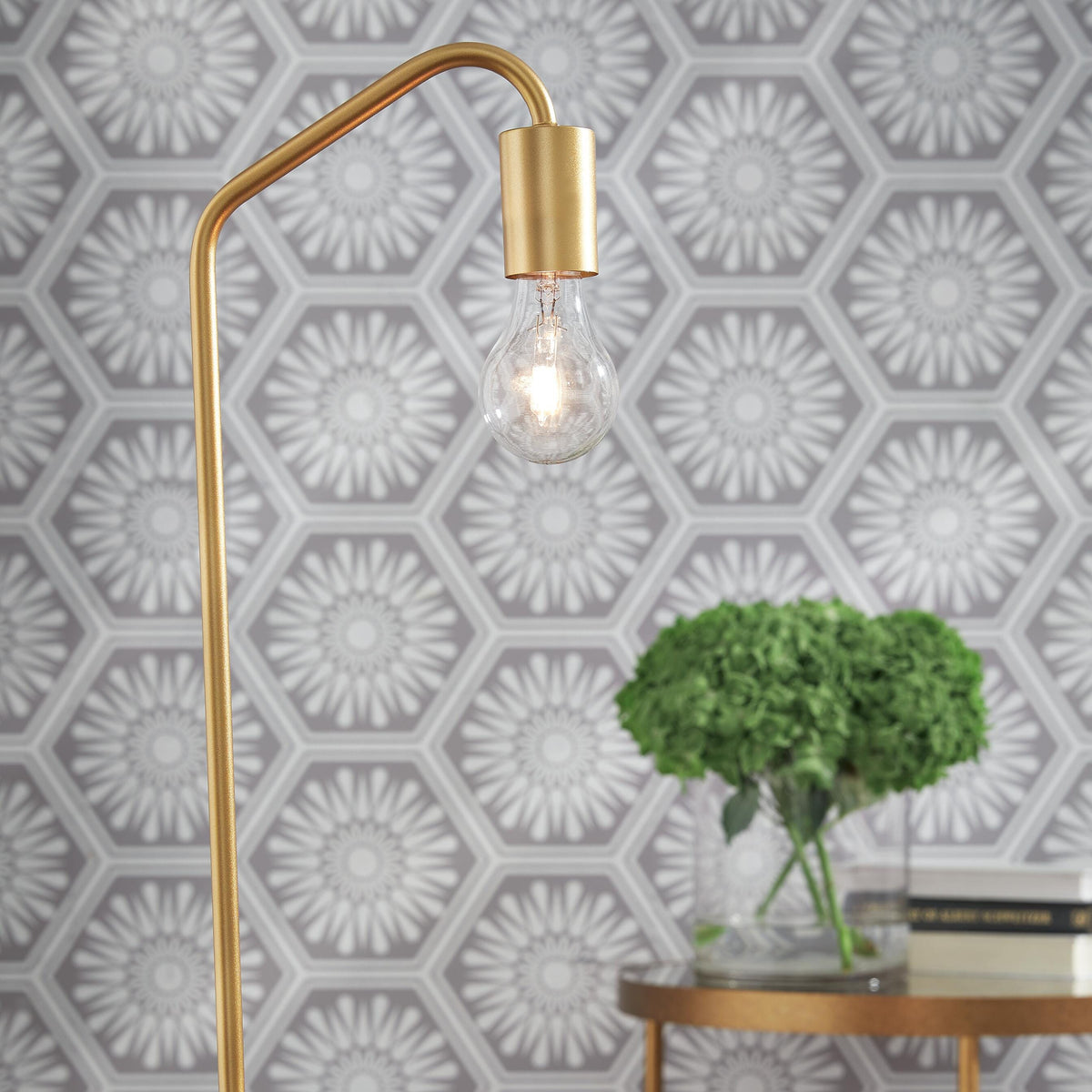 Gold table lamp with a geometric patterned wall in the background