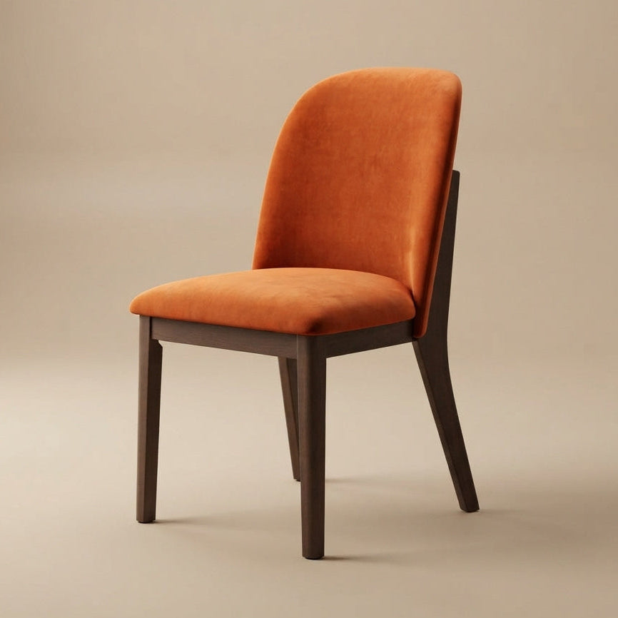 Burnt orange velvet dining chair at a three-quarter angle against a warm beige studio backdrop
