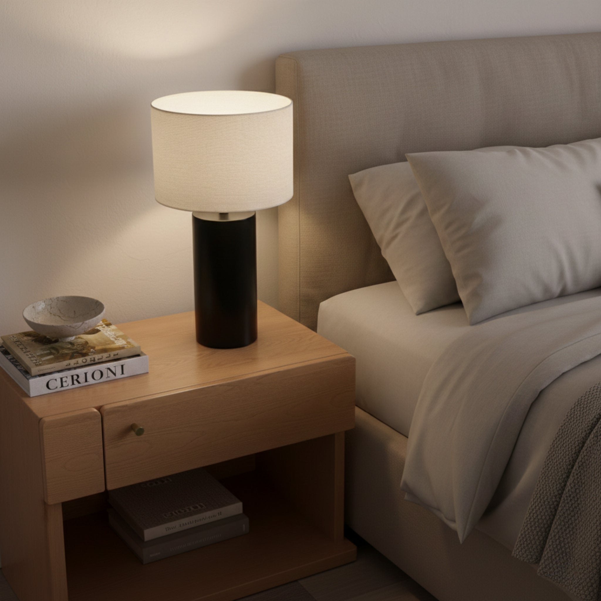 Angled bedside view of the lit Table Lamp on an oak nightstand with books on its lower shelf