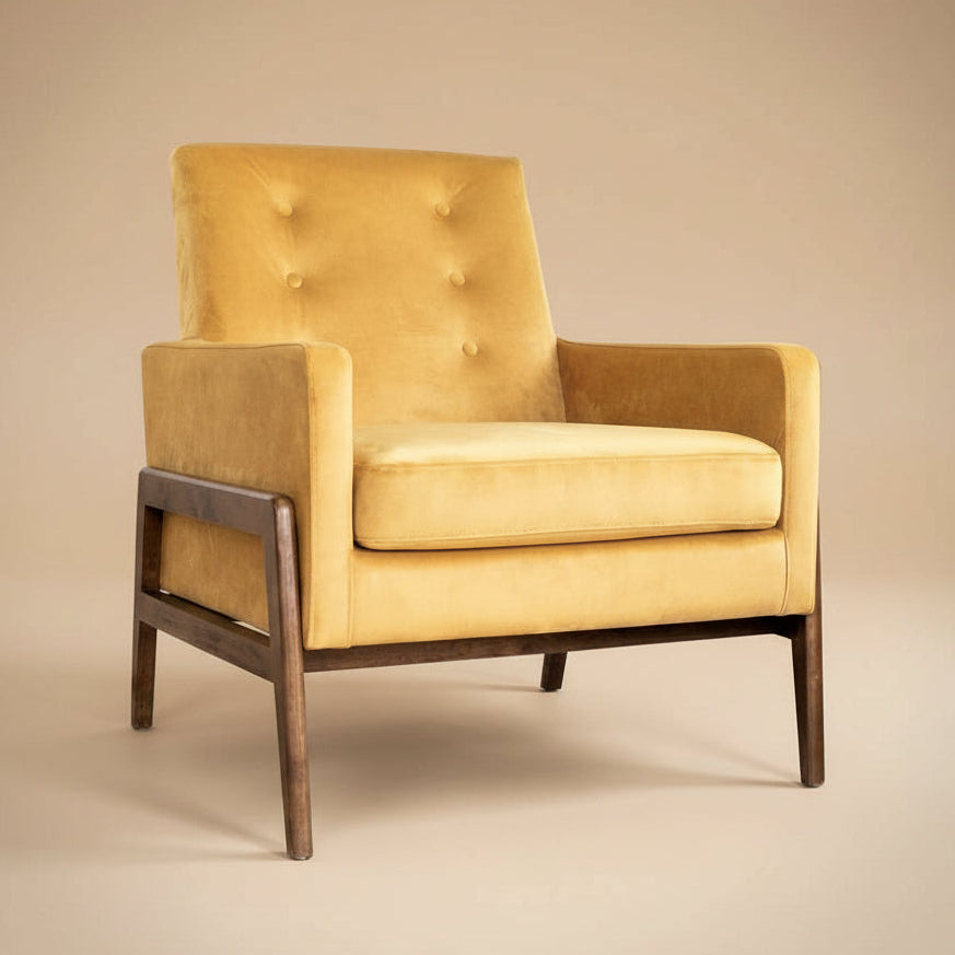 Mustard velvet lounge chair with tufted back and dark wood legs, three-quarter studio shot on a beige backdrop.