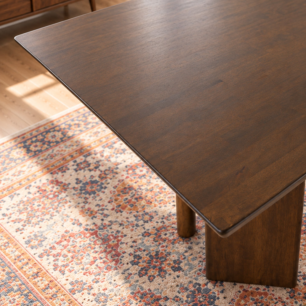 Walnut-toned rectangular dining table with flat panel legs, high angle view.