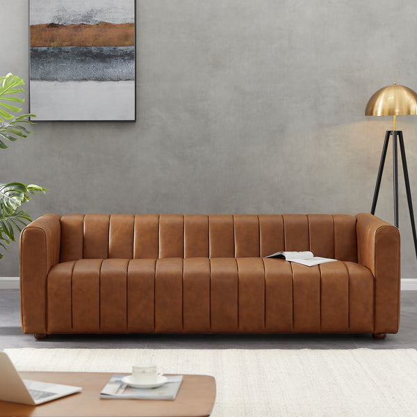 Tan leather sofa in a grey living room with abstract wall art, gold tripod lamp and open book on the seat