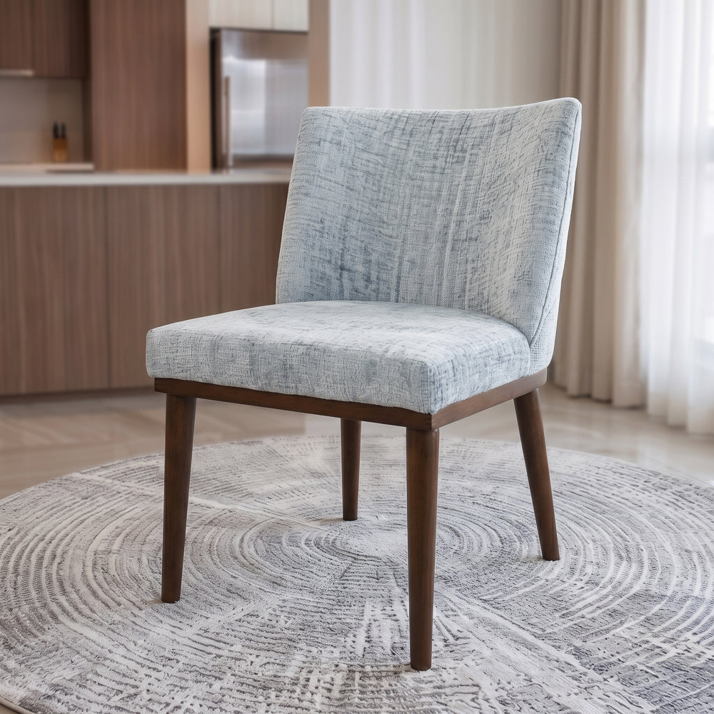 Three-quarter view of a single grey dining chair on a round rug in a dining nook
