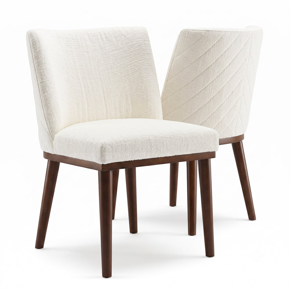 Two dining chairs on white, one facing forward and one turned to show the stitched back