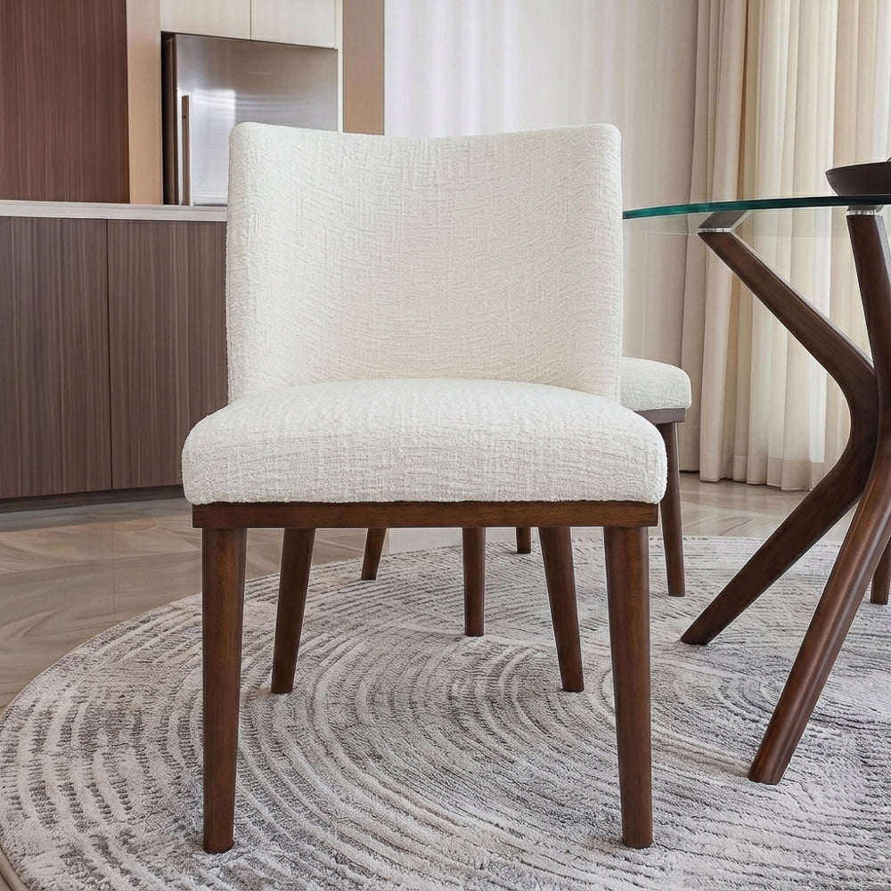 Rear view of the white dining chair beside a glass table, kitchen cabinetry behind