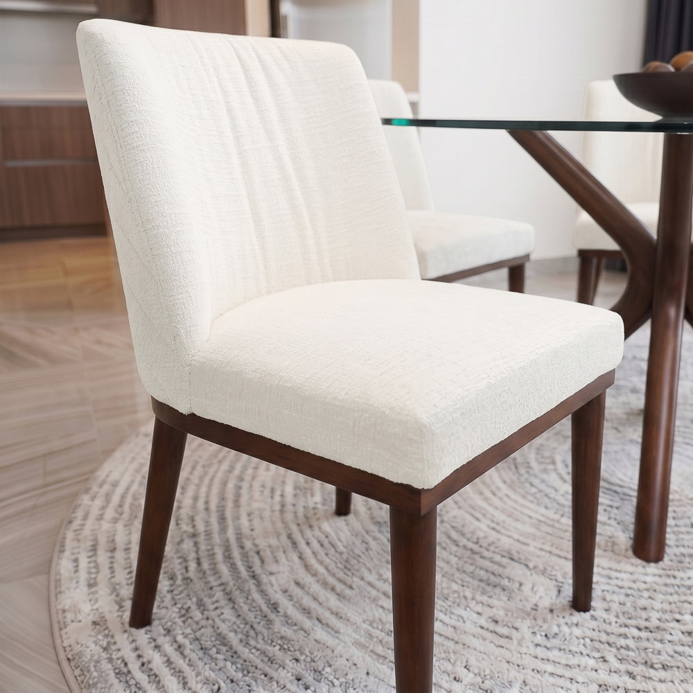 Front-facing dining chair pulled up to a glass table on a round textured rug