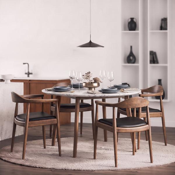 Four Freya chairs around a round marble table set with plates and glasses in a modern kitchen