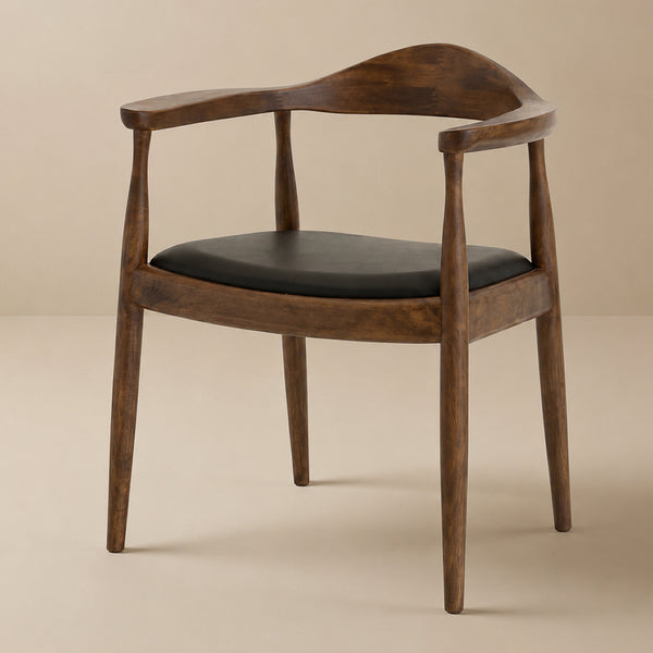 Walnut Freya dining chair with black vegan leather seat, three-quarter studio view on a beige backdrop