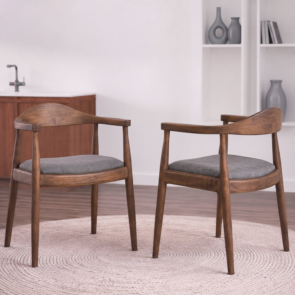 Two Freya dining chairs facing each other on a round beige rug in a kitchen with open shelves.