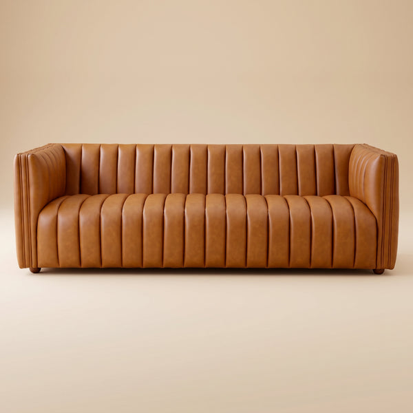 Rosslyn cognac leather sofa, front view on a solid beige studio backdrop, showing vertical channel tufting and block arms.