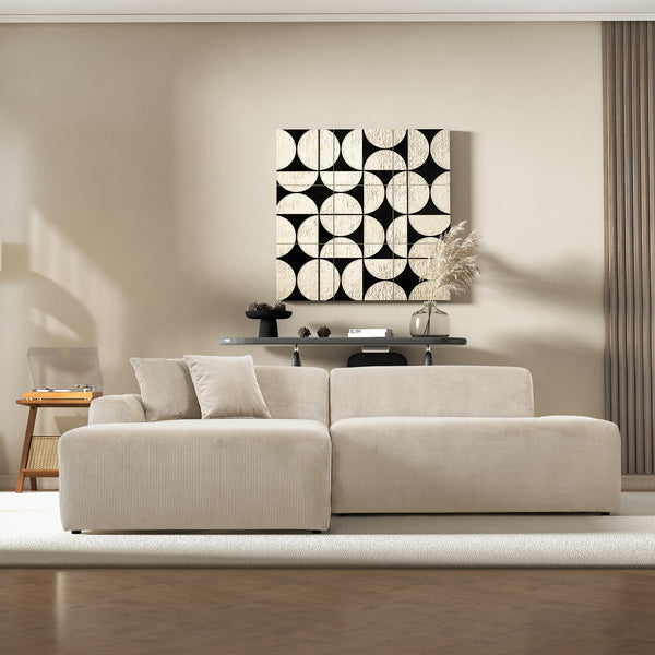 Cream corduroy sectional sofa styled in a living room below a black-and-white geometric wall art panel