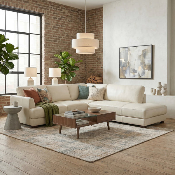 Cream sectional sofa styled with throw pillows and a green blanket in a brick loft living room